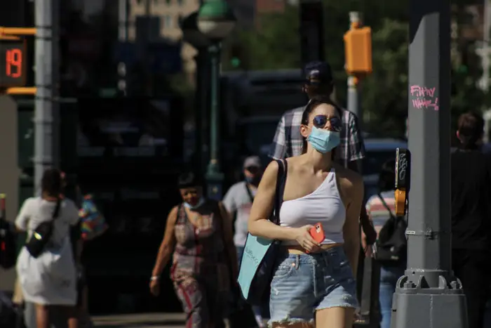 a woman crosses a Manhattan street holding a cell phone